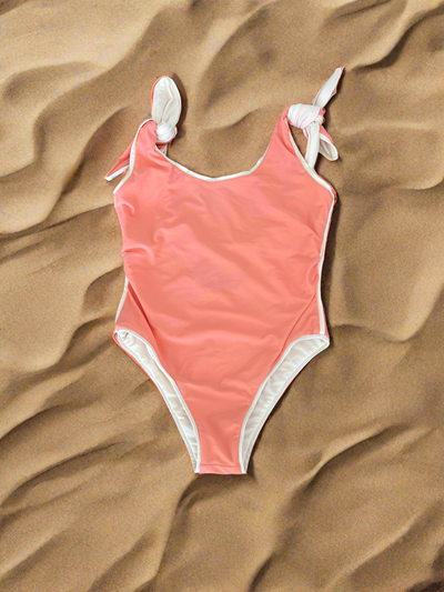 Paper London one-piece swimsuit in peach and cream on sand background, size medium.