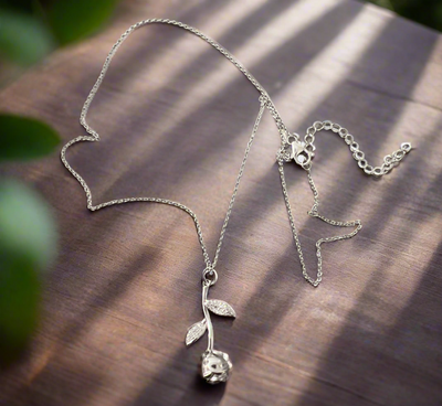 The Carolina Rose Silver Necklace with Crystal on a wooden surface.